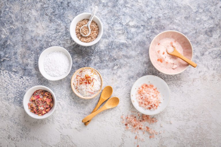 assortment of gourmet salts in small bowls, including himalayan and rose petal infused